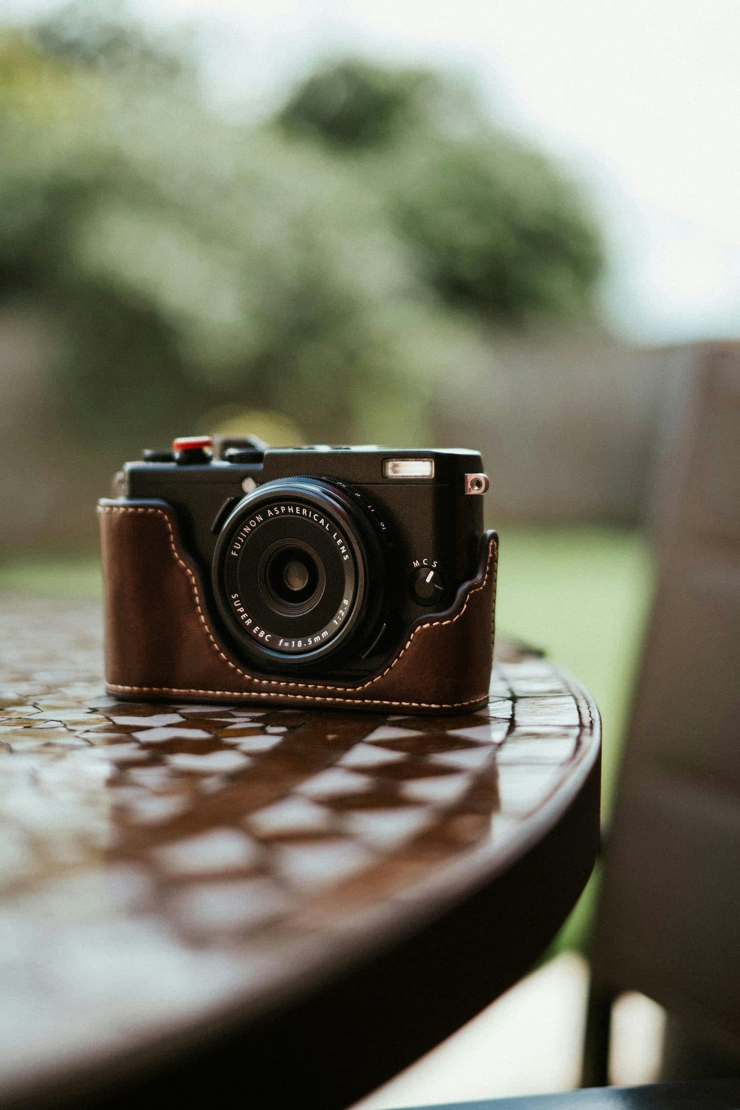 Fujifilm X100VI in a coffee leather half case on a warm cream backdrop